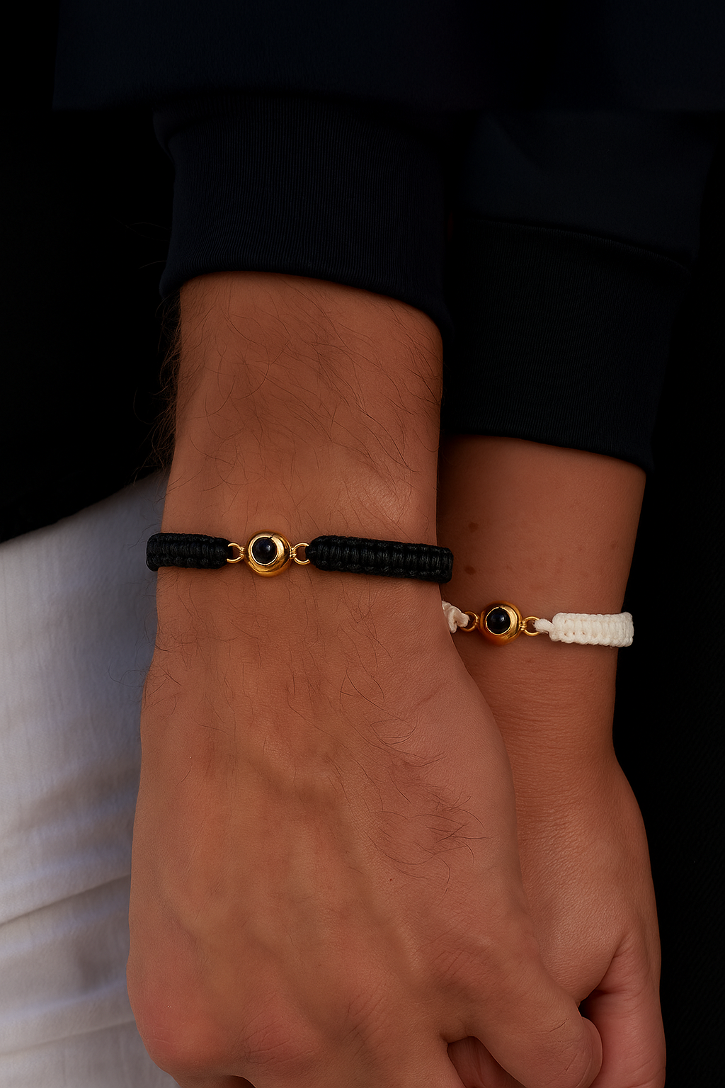 Two hands wearing personalized Stanbarry bracelets - one black and one white with gold photo elements